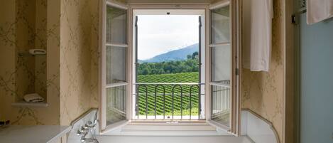 A bathroom with a window view of a green landscape.