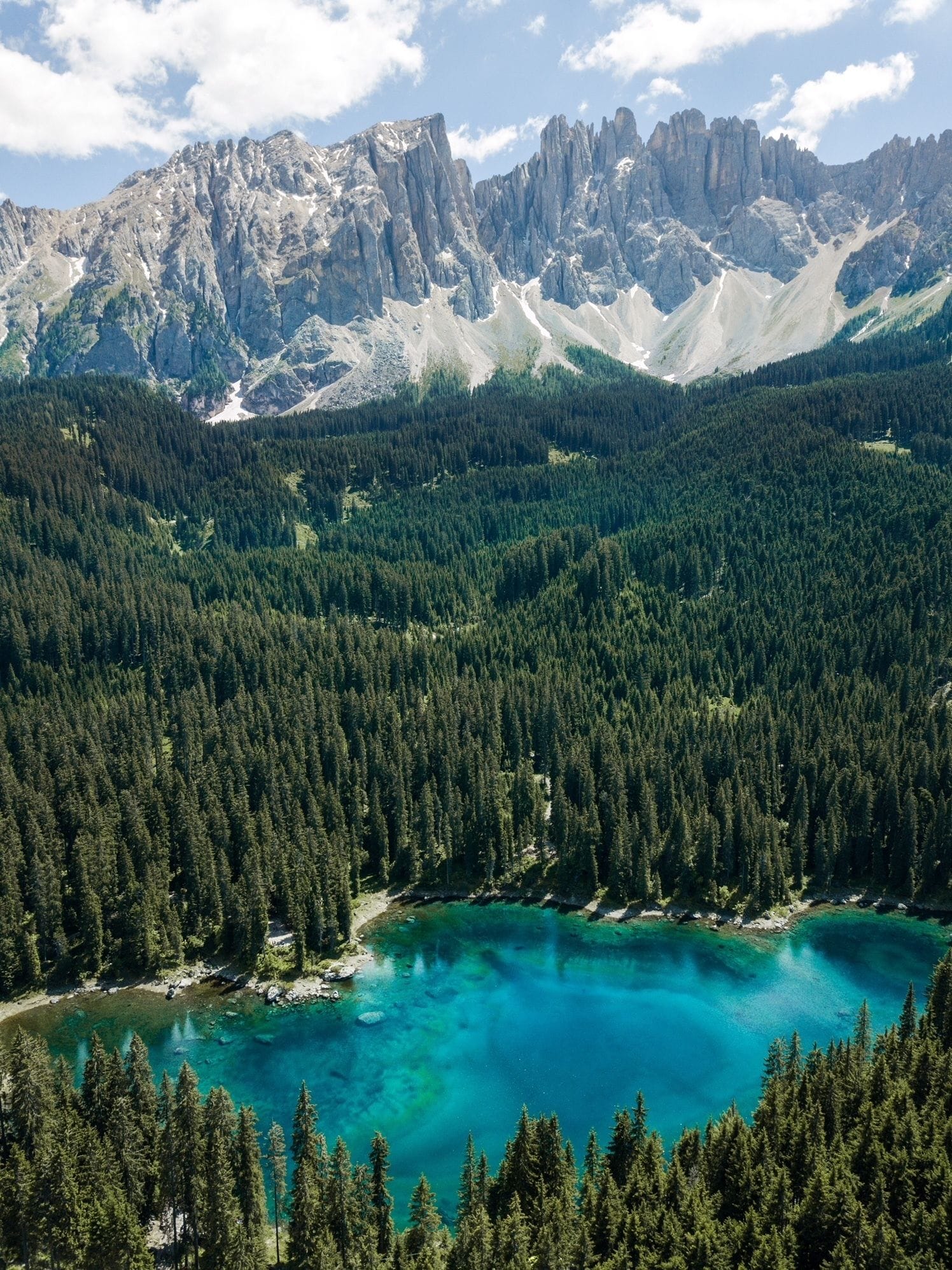 Eine bergige Landschaft mit dichten Wäldern und einem türkisfarbenen See.
