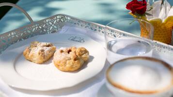 A tray with pastries and a cup of coffee, a rose in a glass, and a menu on a table.