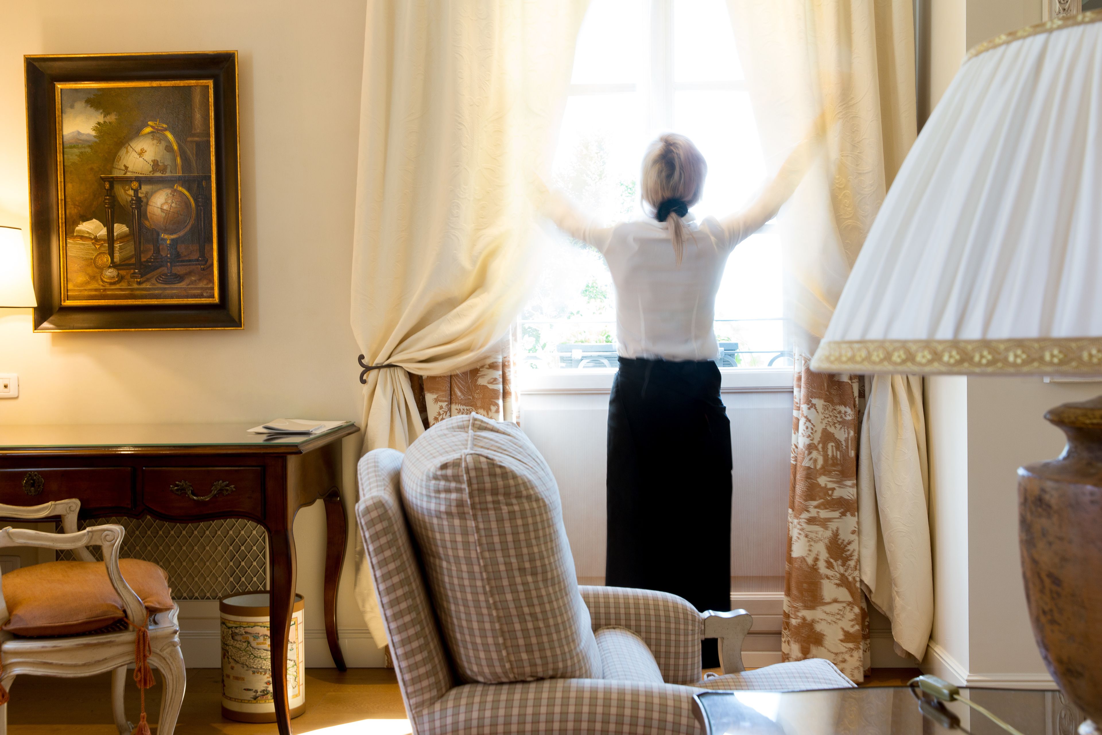 Une pièce avec une grande fenêtre, une chaise, un bureau et une lampe.