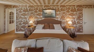 A bedroom with a large bed, two bedside tables with lamps, a framed picture on the wall, and a patterned wallpaper.