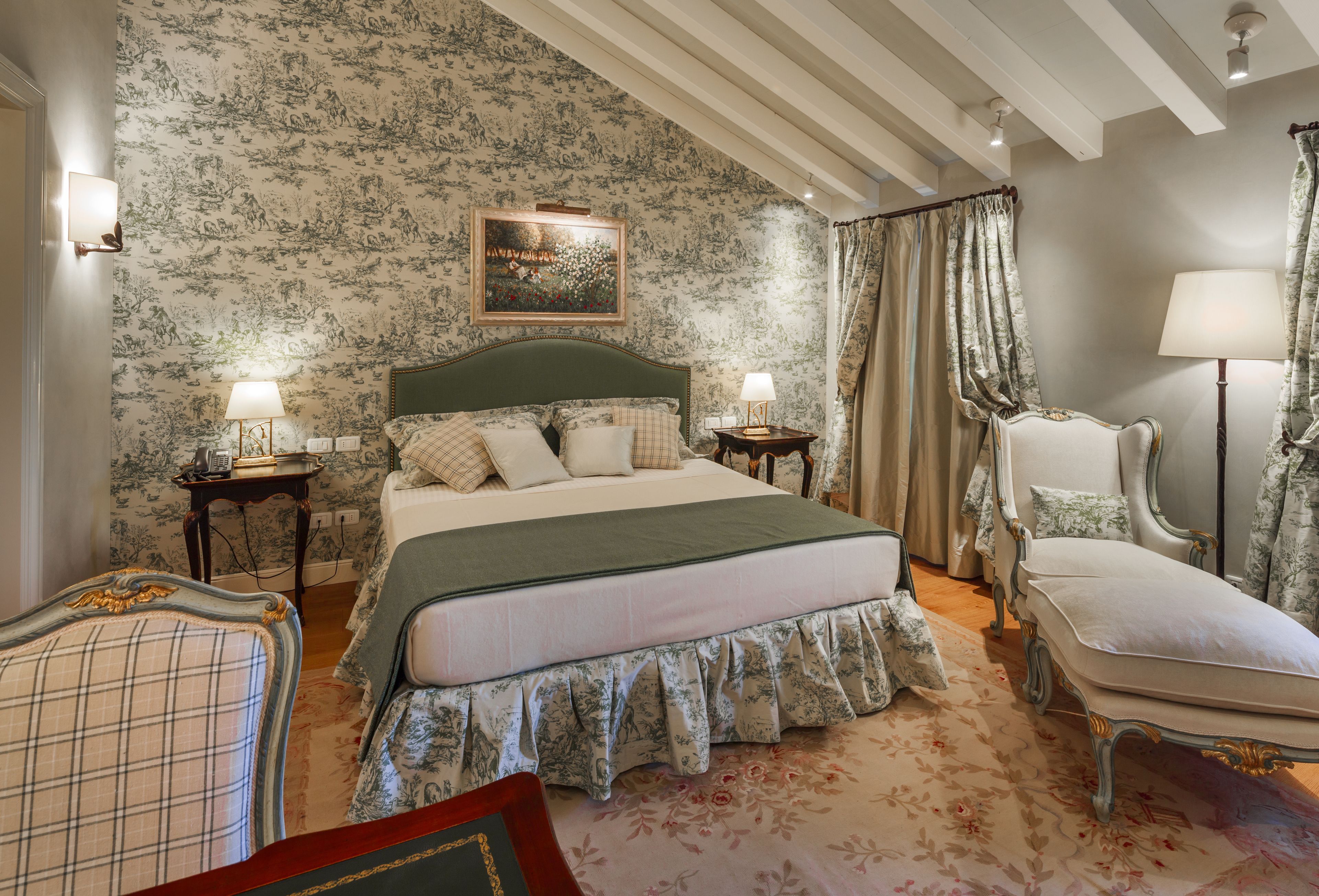 Une chambre à coucher classique, avec un grand lit, deux tables de chevet, une chaise et une petite table d’appoint.