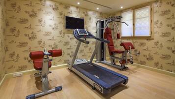 A home gym with a treadmill, weight bench, and exercise machine.