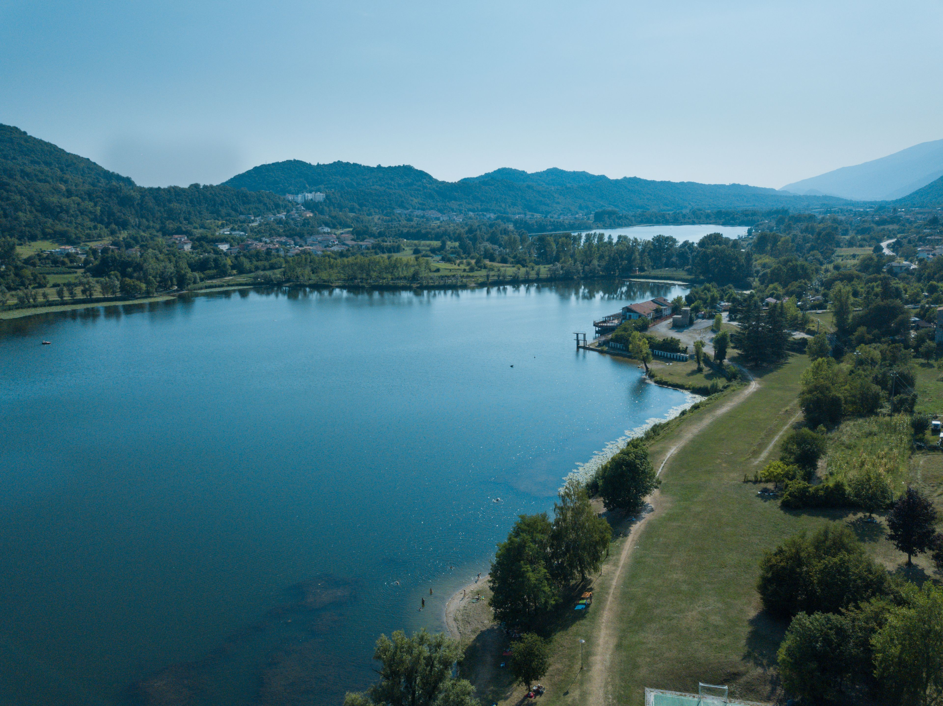 An aerial view of a lake surrounded by hills, with a small dock and a few buildings near the shore.