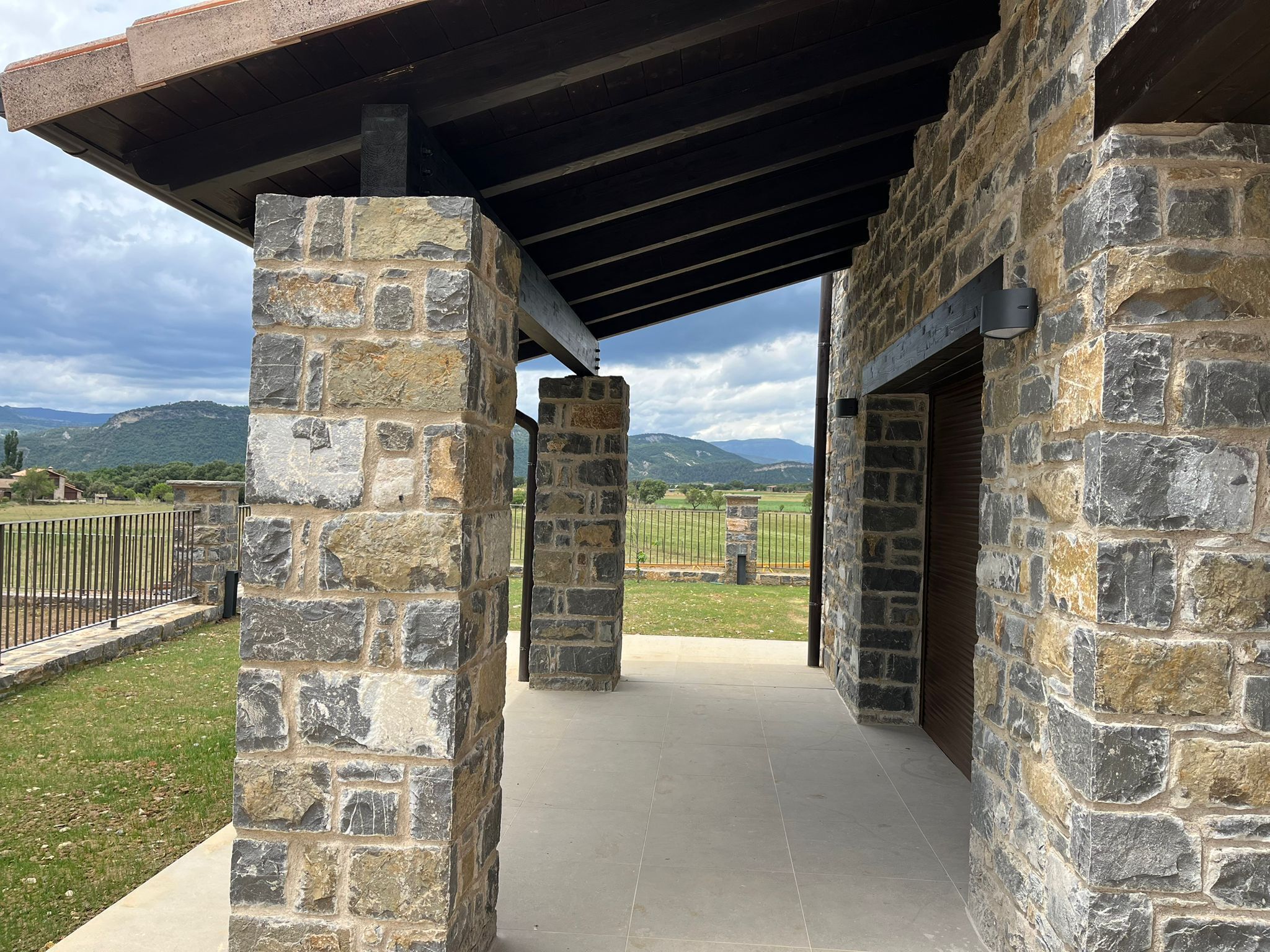 Ein Steinhaus mit einer überdachten Terrasse und Blick auf die Landschaft.