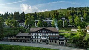 Ein modernes Hotel mit einer Steinfassade, mehreren Stockwerken und einem markanten Schornstein, der Rauch abgibt.