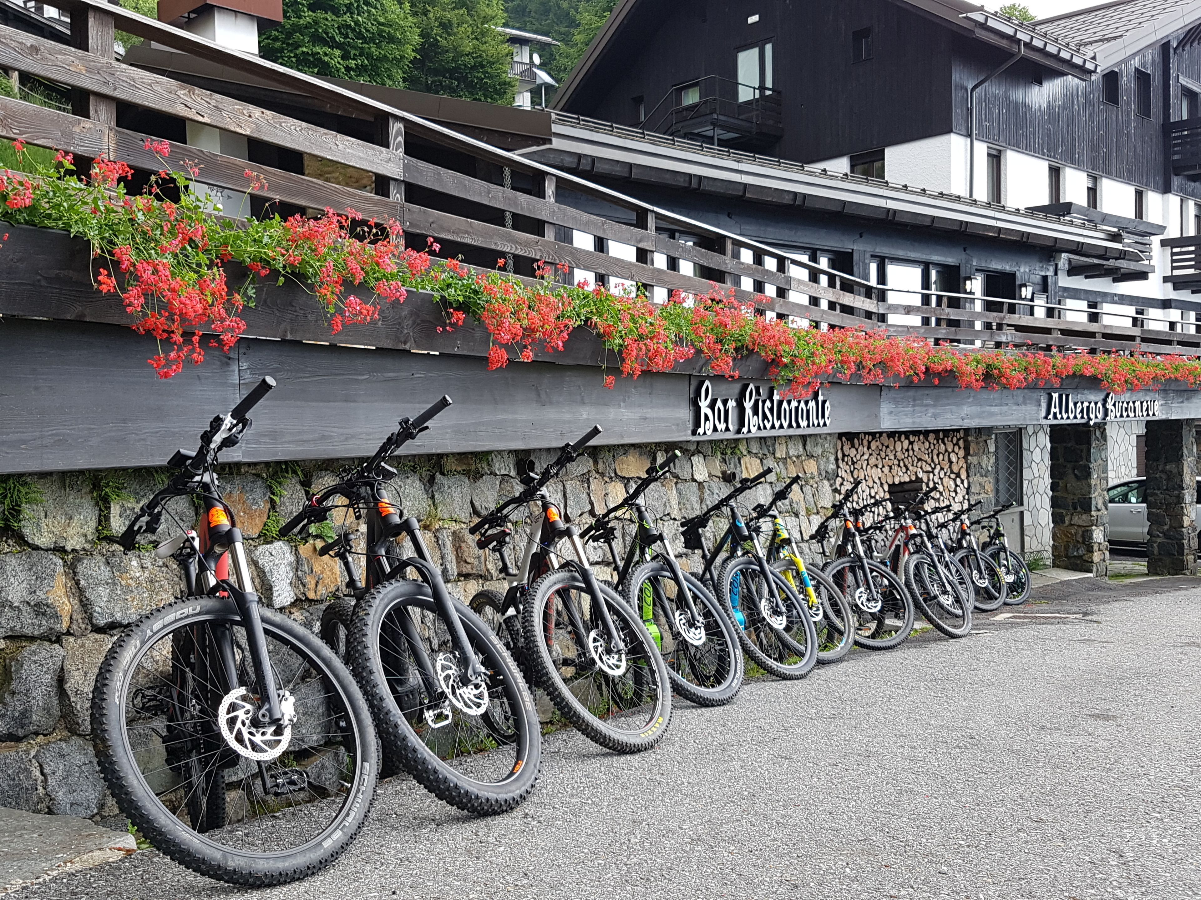 Une rangée de vélos est garée contre un mur de pierre, et une enseigne indiquant « Bot Ristorante » est placée au-dessus.