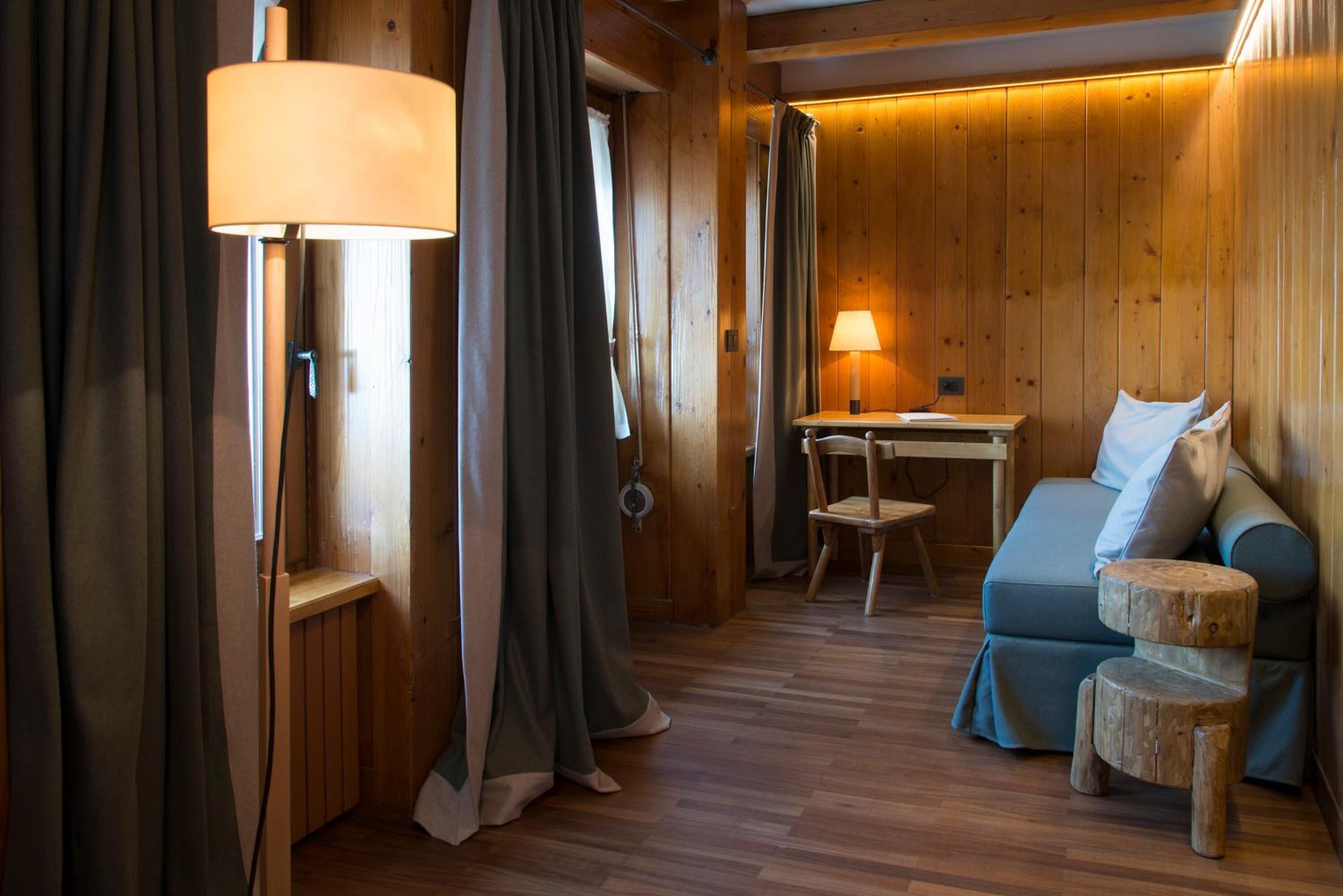 Une pièce chaleureuse avec des murs en bois, un canapé bleu, une petite table en bois et une lampe.