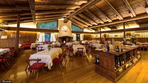 Ein geräumiges Restaurant mit Holzbalken, mehreren Tischen und einem zentralen Kamin.