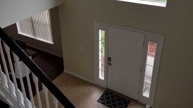 A staircase leading to a door with a view of a driveway and a parked car outside.