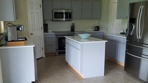 A modern kitchen with grey cabinets, stainless steel appliances, and a central island.