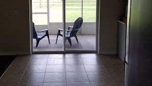 A kitchen with a refrigerator, a sliding glass door leading to a patio with two chairs.