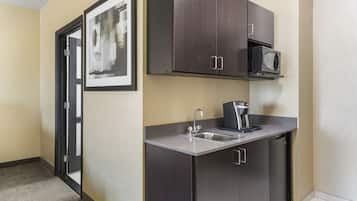 A compact kitchen with a microwave, sink, and dark cabinets.