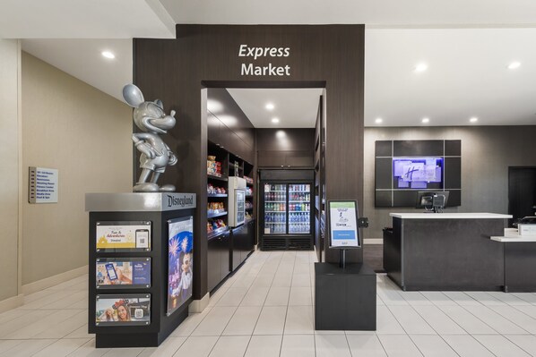 Uma loja Express Market moderna com uma estátua do Mickey Mouse, balcões refrigerados e uma tela digital.