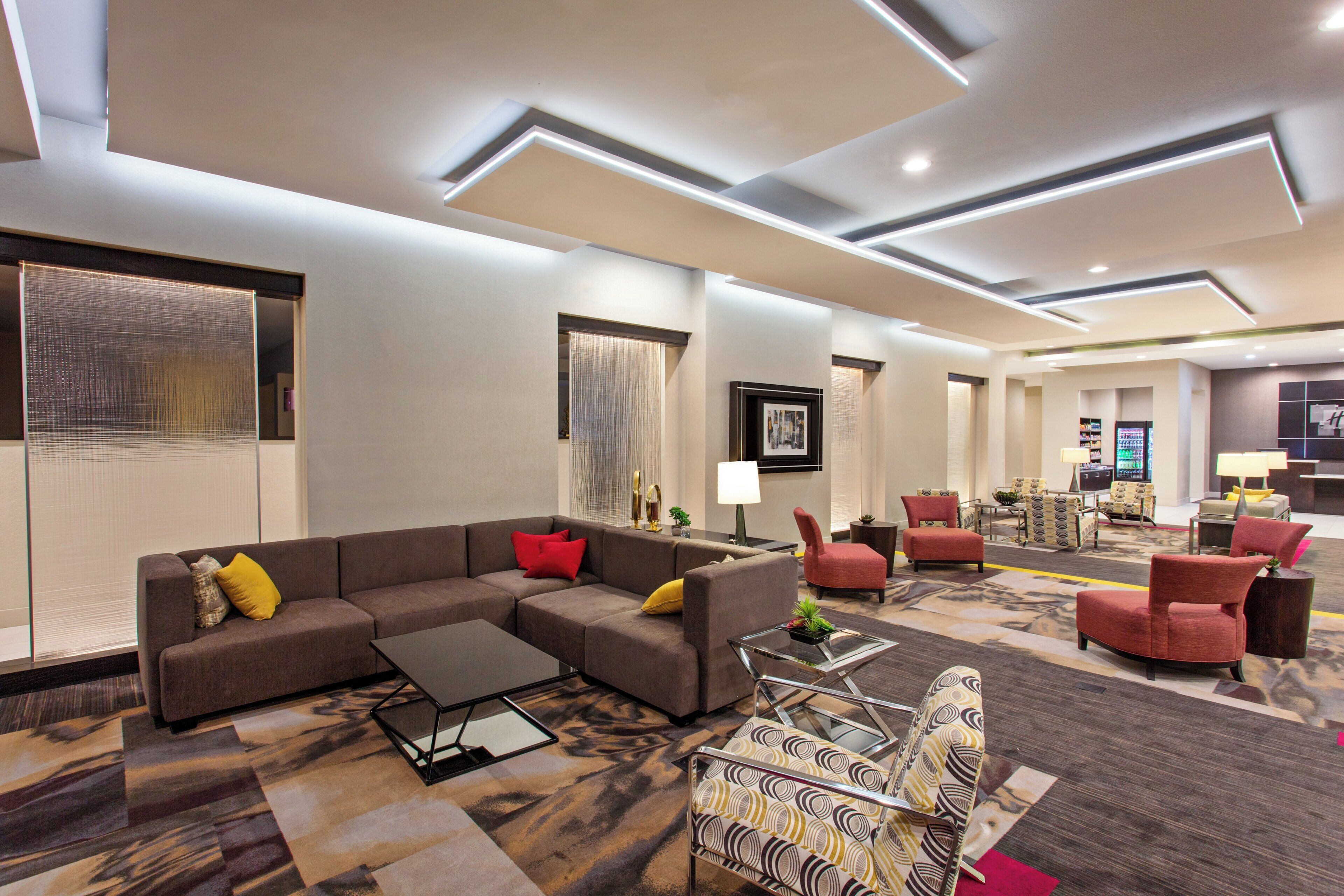 Un vestíbul d'hotel modern amb un sofà modular, butaques, una taula de centre i una catifes amb disseny.