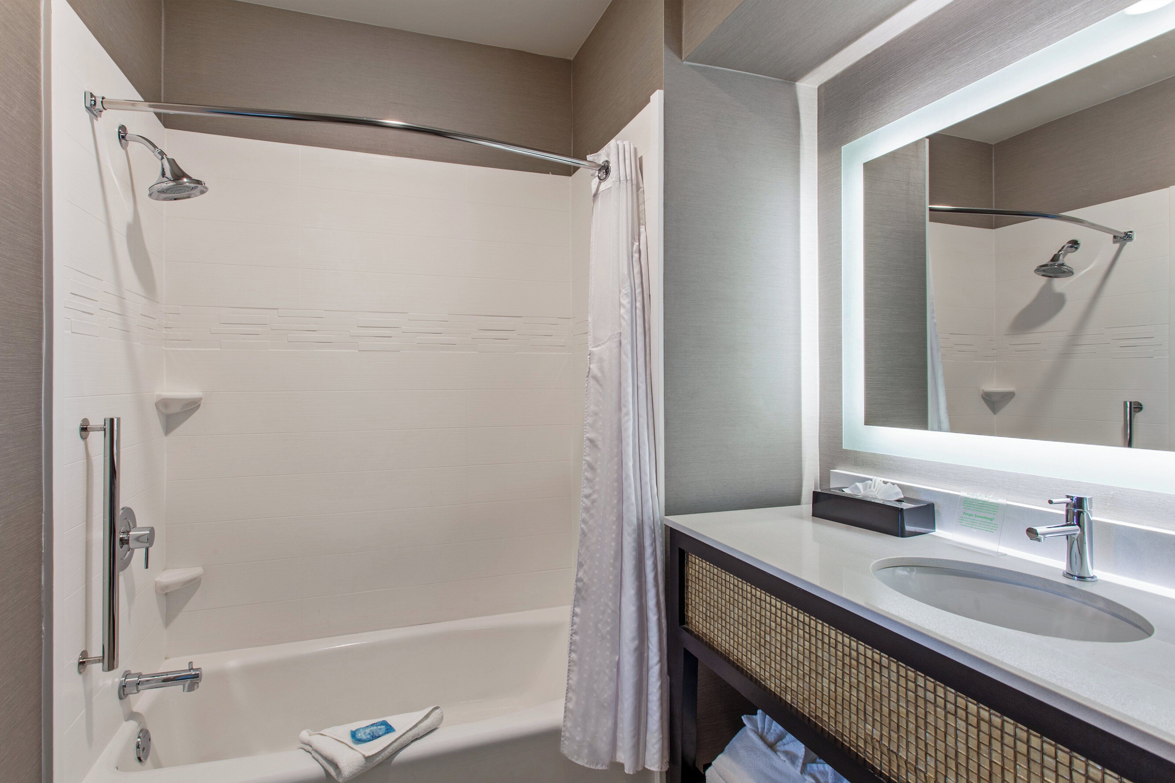 A modern bathroom with a bathtub, a shower, a sink, and a mirror.
