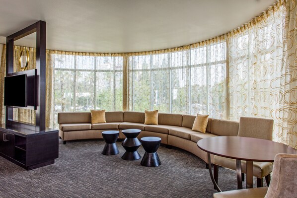 Un salon moderne avec un canapé aux lignes courbes, un téléviseur à écran plat et une table ronde.