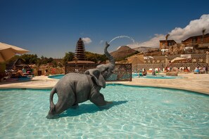 A pool area with a large elephant statue, a pagoda-style building, and a clear blue sky.