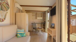 A cozy room with a sofa, a small table, and a chair. There is a kitchenette area with cabinets and a countertop. - Magic Natura Animal, Waterpark & Polynesian Resort (Benidorm)