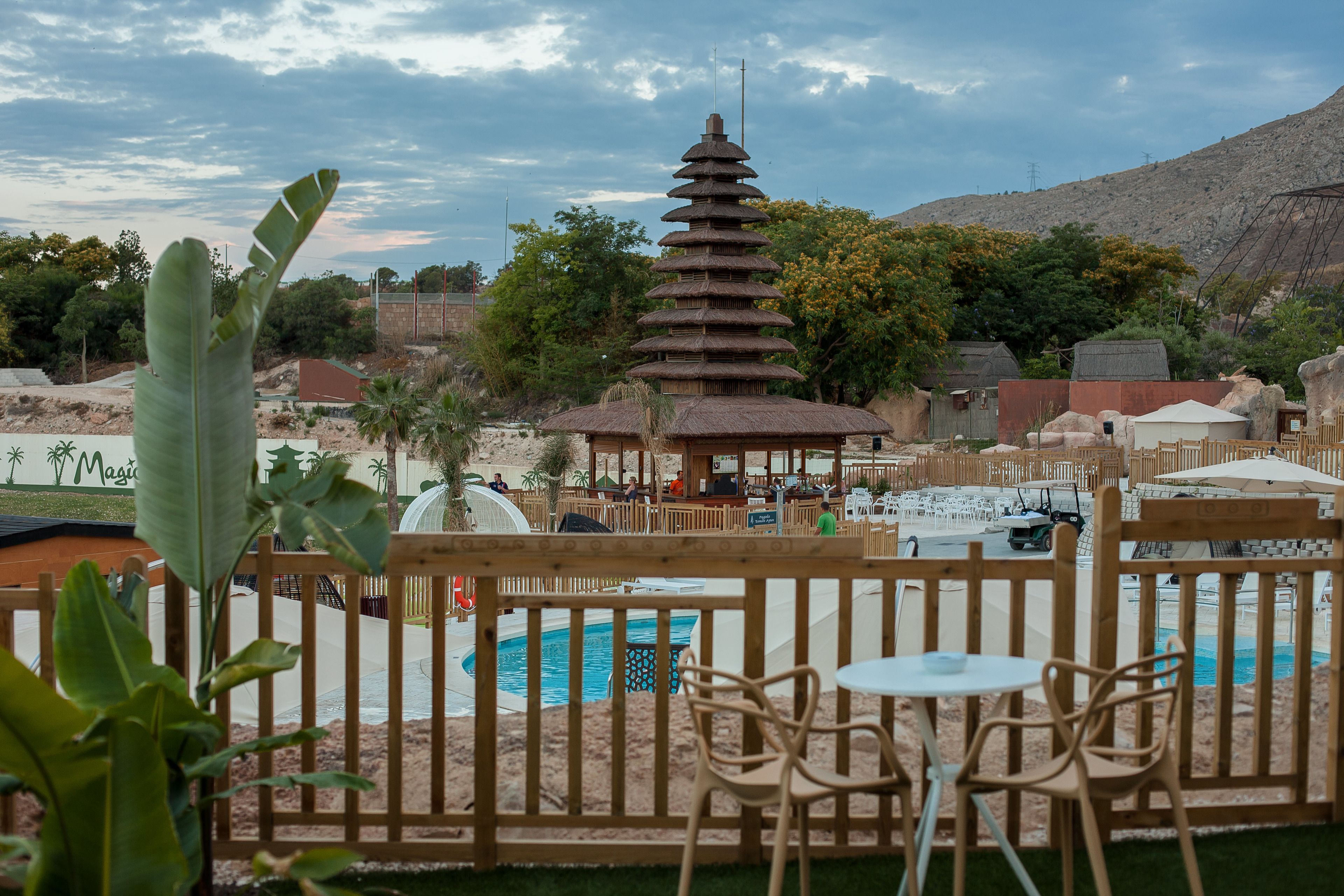 Zona de piscina con valla de madera, una estructura similar a un pabellón y vistas a un paisaje montañoso.