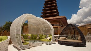 A modern outdoor seating area with wicker furniture and a unique architectural structure in the background. - Magic Natura Animal, Waterpark & Polynesian Resort (Benidorm)