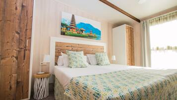 Una habitación de hotel con una cama grande, un cabecero de madera, una mesita de noche, una lámpara y un cuadro de una pagoda en la pared.