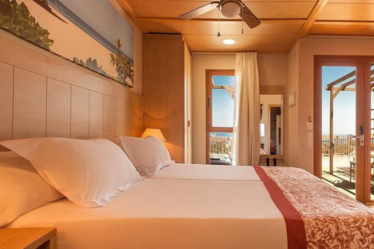 Ein Hotelzimmer mit Bett, Deckenventilator und Blick ins Freie.