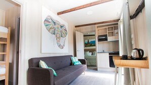 A compact living space with a sofa, a coffee table, and a kitchen area with a refrigerator and a kettle. - Magic Natura Animal, Waterpark & Polynesian Resort (Benidorm)