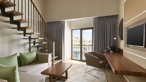 A modern living room with a staircase, a sofa, a coffee table, a TV, and a balcony with curtains.