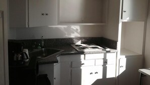 A kitchen with white cabinets, a granite countertop, and a gas stove. - Lake Marina Inn (Clearlake Oaks)