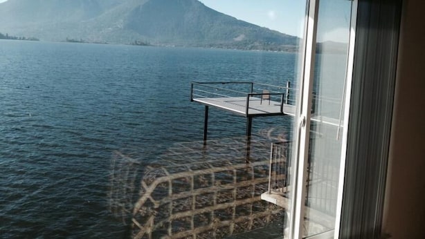 A view from a window overlooking a calm lake with mountains in the background. - Lake Marina Inn (Clearlake Oaks)