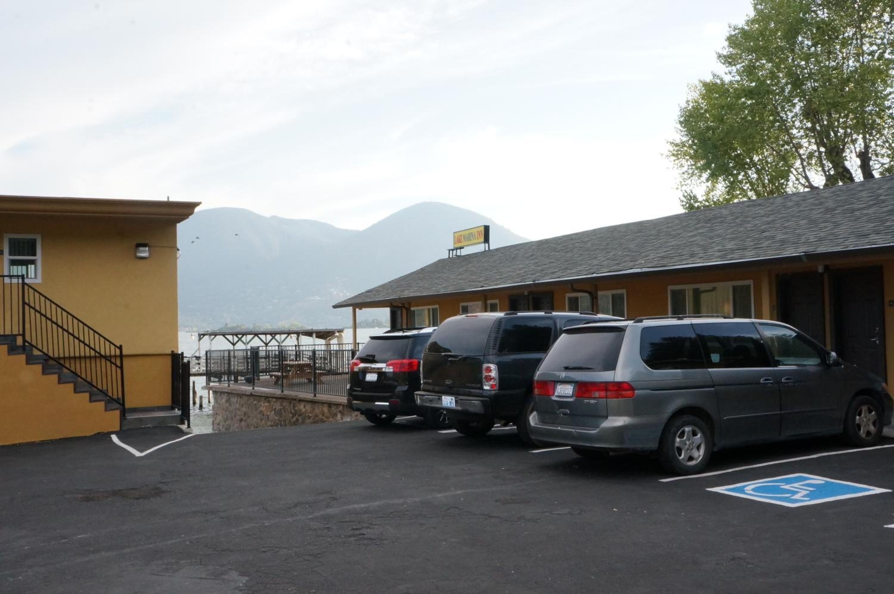 A parking area with three cars, a building with a ramp, and a view of mountains.