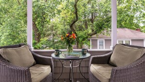 A wicker sofa set with cushions, a small round table, and a vase with flowers.