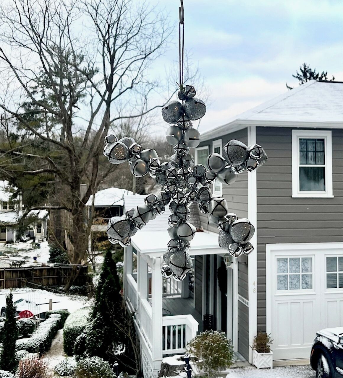 A snowflake-shaped decoration hanging outside a house with a garage and a covered porch.