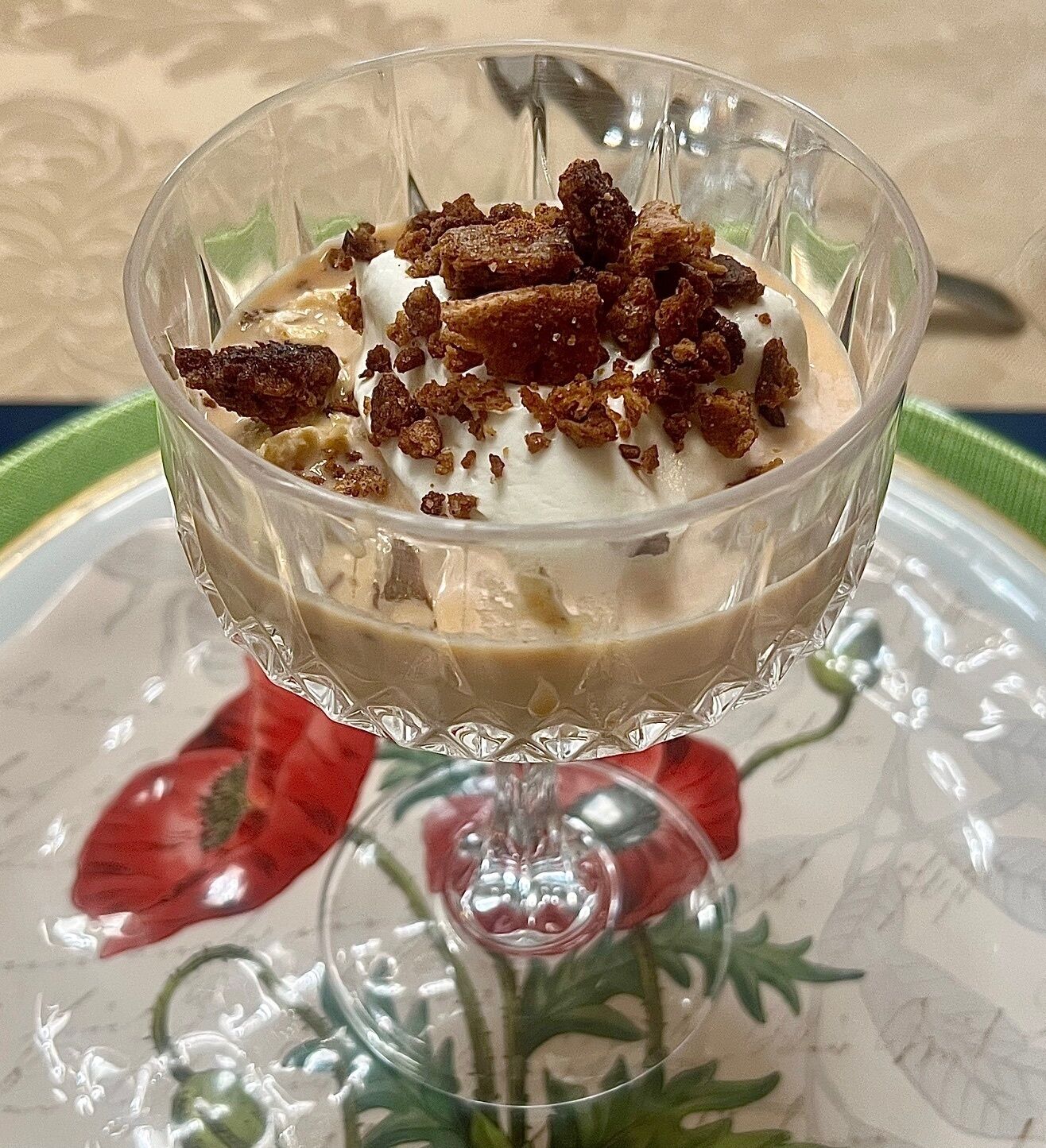A dessert in a glass bowl on a table with a floral pattern.
