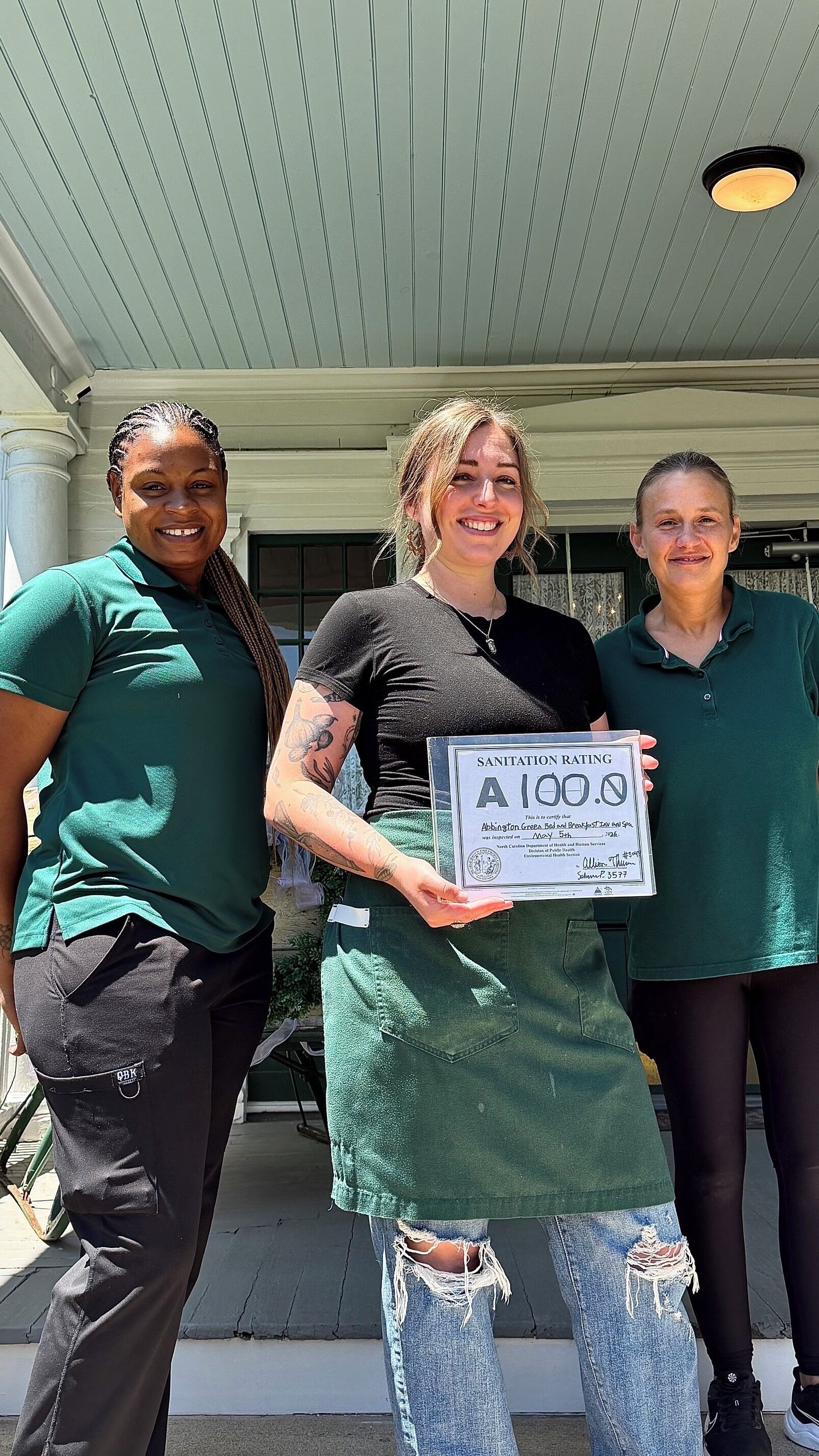 Three individuals holding a sanitation rating certificate.