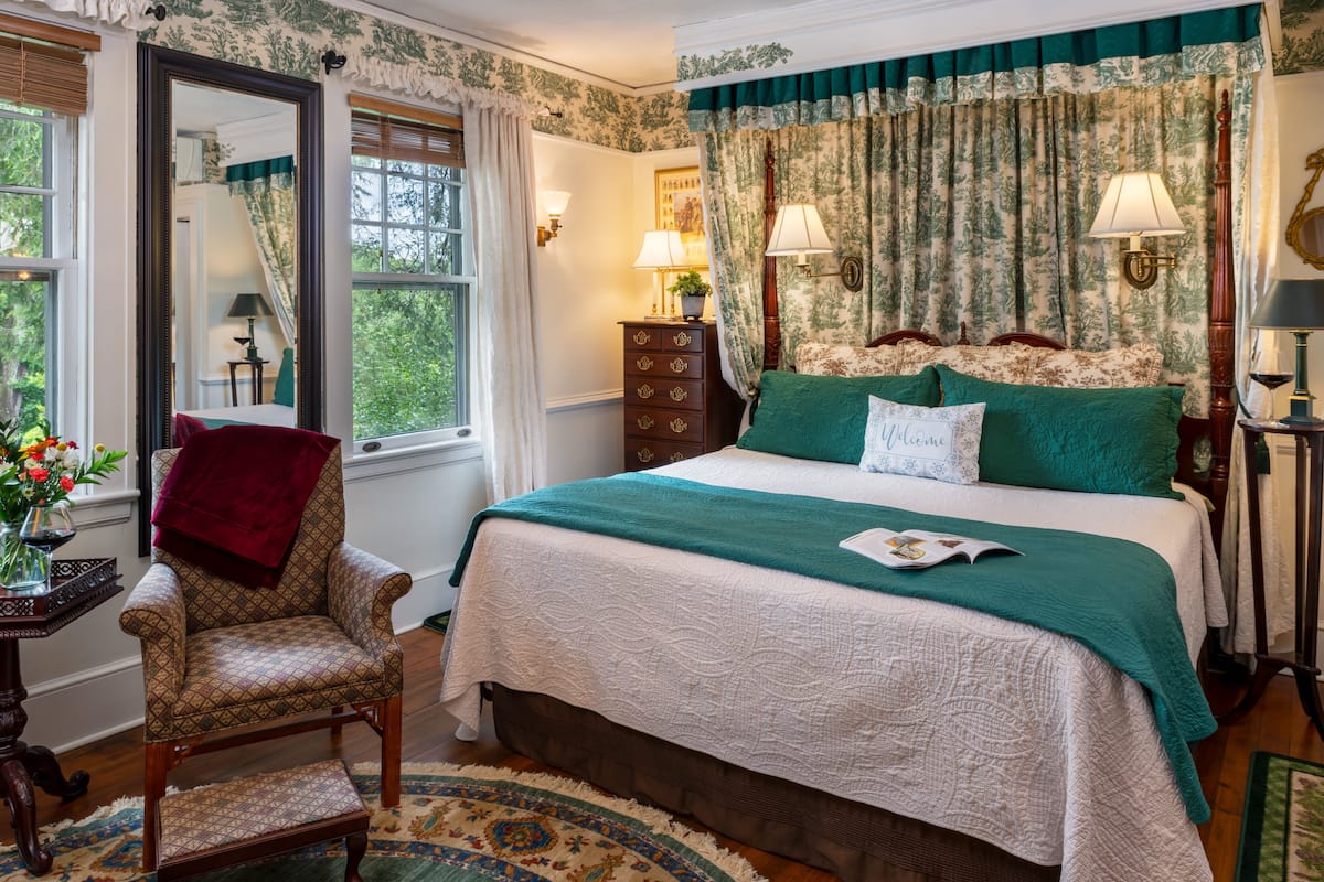 Une chambre à coucher avec un grand lit, une chaise, une commode et un miroir.