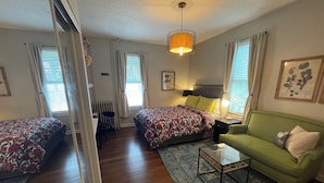 A room with two beds, a green sofa, a small table, and a ceiling light. - Modern Homestead Guest House (Reedsville)