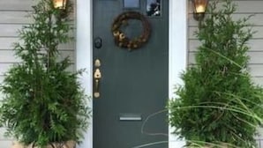 A front door with a wreath, two small trees, and pumpkins on the porch. - Modern Homestead Guest House (Reedsville)