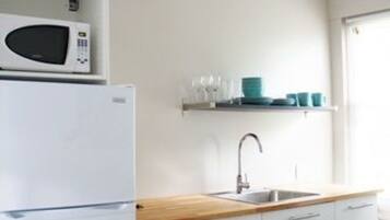 Una cucina moderna con mobili bianchi, un forno a microonde e un lavandino.