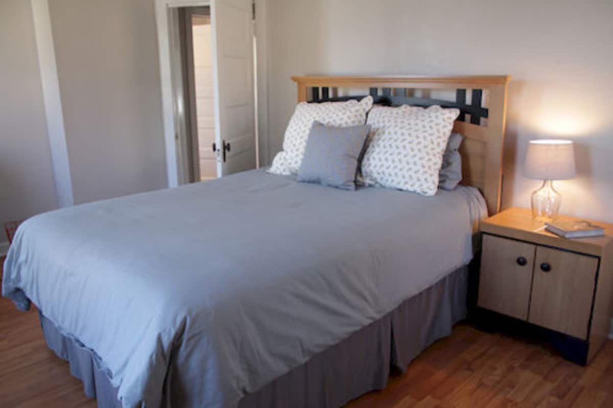 A bedroom with a bed, bedside table, and nightstand.