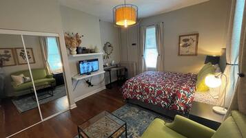 Un dormitorio moderno con una cama, un sofá verde, un televisor y un escritorio.