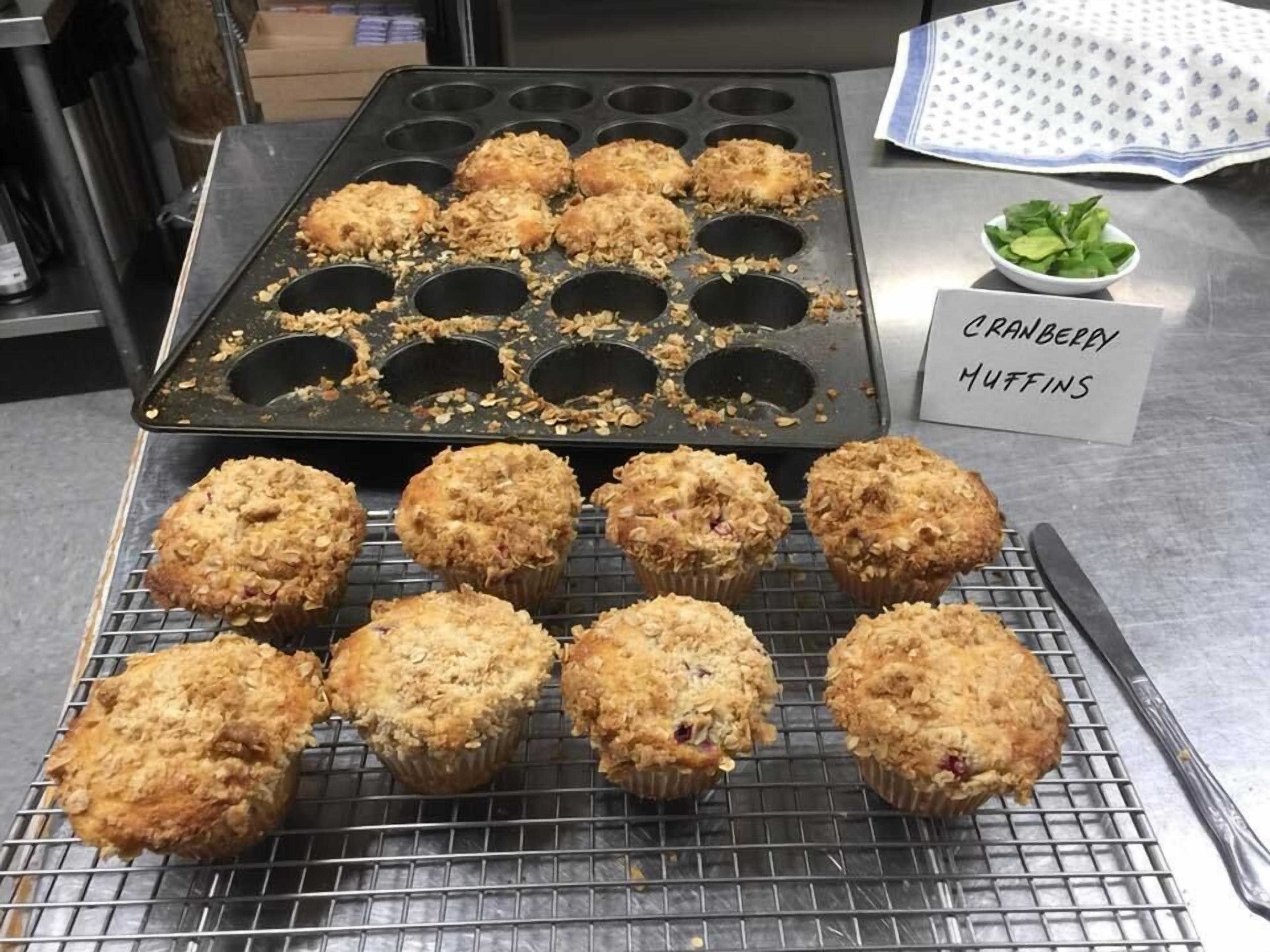 A muffin tray with muffins on a cooling rack and a label reading "cranberry muffins".