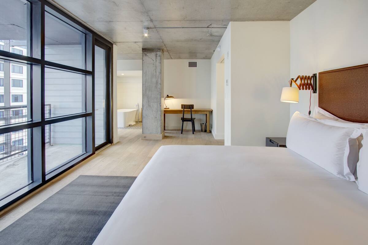 Hotellihuone, jossa on suuri sänky, työpöytä ja tuoli.