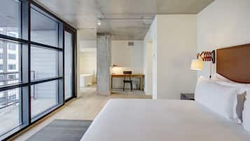 A hotel room with a large bed, a desk, and a chair.