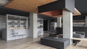 A modern interior with exposed concrete pillars, a central seating area, and built-in bookshelves. - The Boro Hotel (Long Island City)
