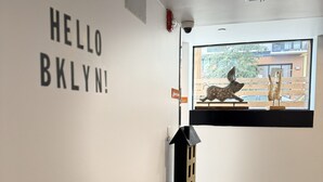 A modern interior with a black counter, a potted plant, and a window with a view of a building and a sculpture.