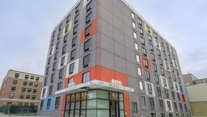 A multi-story hotel with a modern design, featuring a prominent entrance with glass doors and a sign indicating it is a hotel.