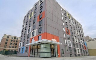 A multi-story hotel with a modern design, featuring a prominent entrance with glass doors and a sign indicating it is a hotel.