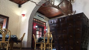 Quarto com teto de madeira, grande cômoda escura e cadeiras de vime.